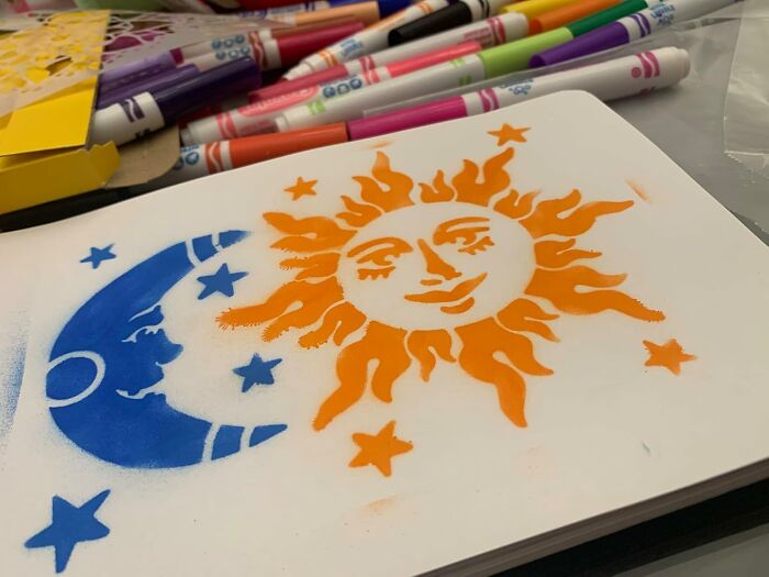 Sun and moon stencil art in orange and blue with markers nearby showcasing creative Cyber Monday deals projects.