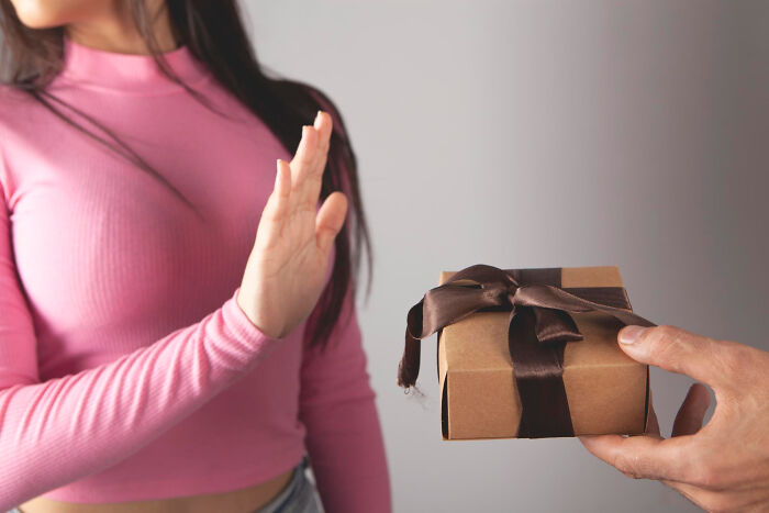 Young woman in pink top rejecting a gift, illustrating signs a child was never loved properly and emotional distance.