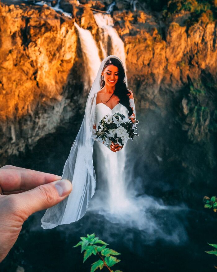 Hand holding a paper cutout of a bride interacting with a real waterfall background in creative paper cutouts art.