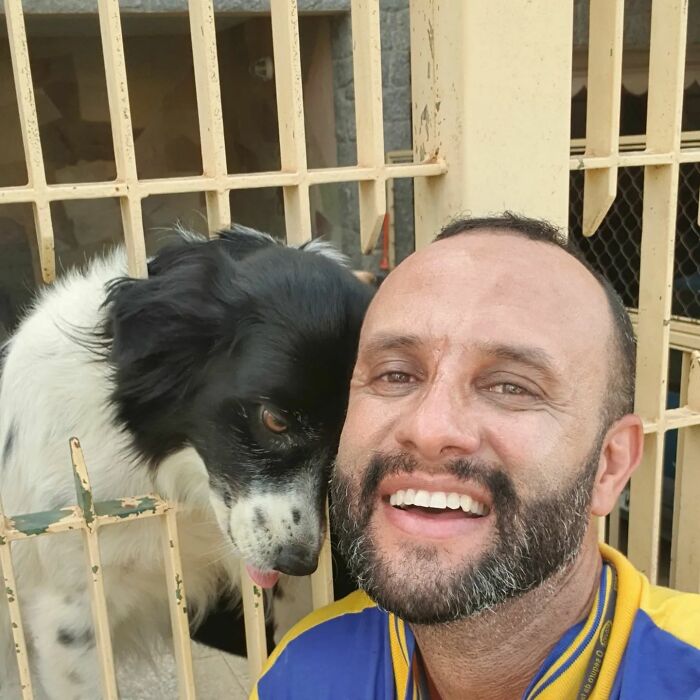 Mailman smiling with a black and white dog showing friendship on his daily delivery route.