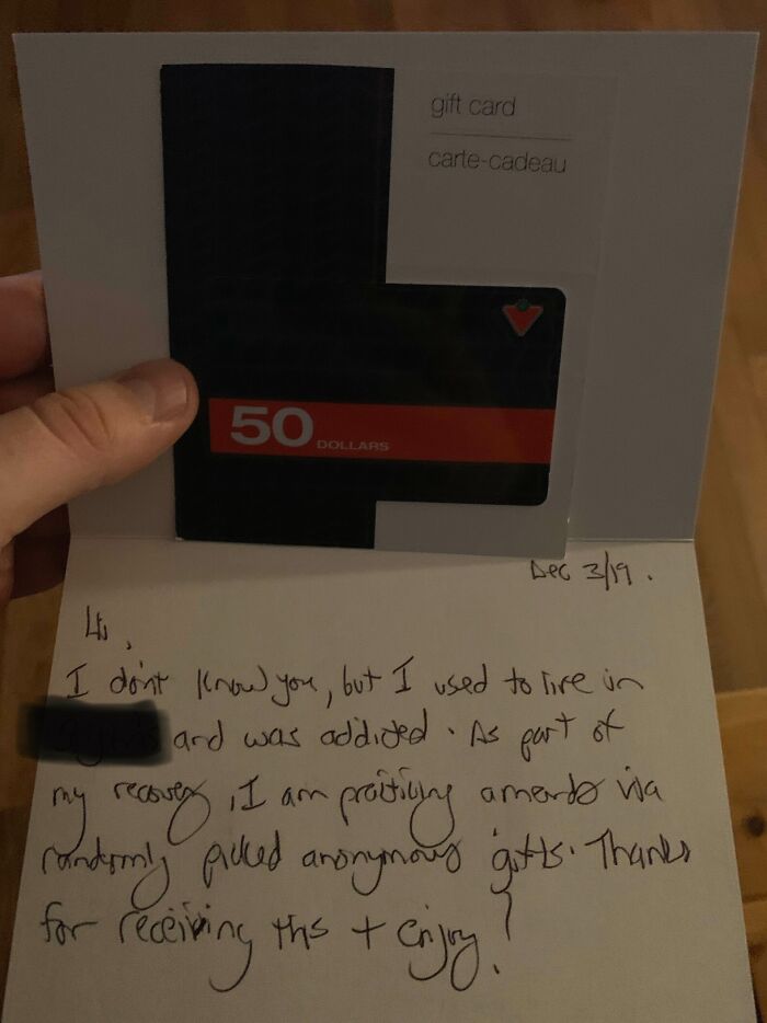 Hand holding a $50 gift card with a handwritten note showing strangers making each other's day, faith in humanity restored.