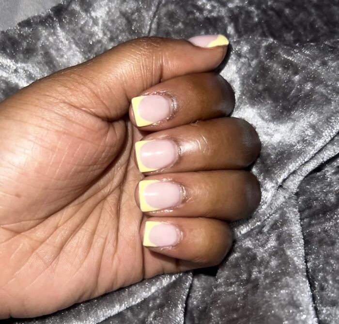 Close-up of a hand with yellow-tipped nails showcasing a creative hobby to keep your hands busy during hibernation season.