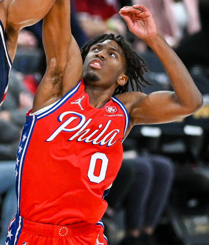Tyrese Maxey in a Philadelphia 76ers jersey jumping to make a basketball play during an intense game moment.