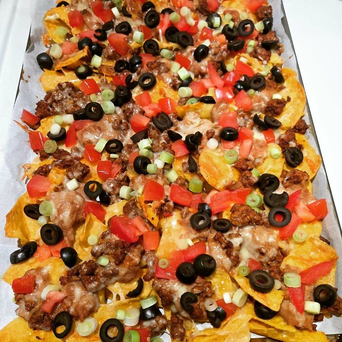 Loaded nachos with ground beef, melted cheese, olives, tomatoes, and green onions representing girl dinner combos.
