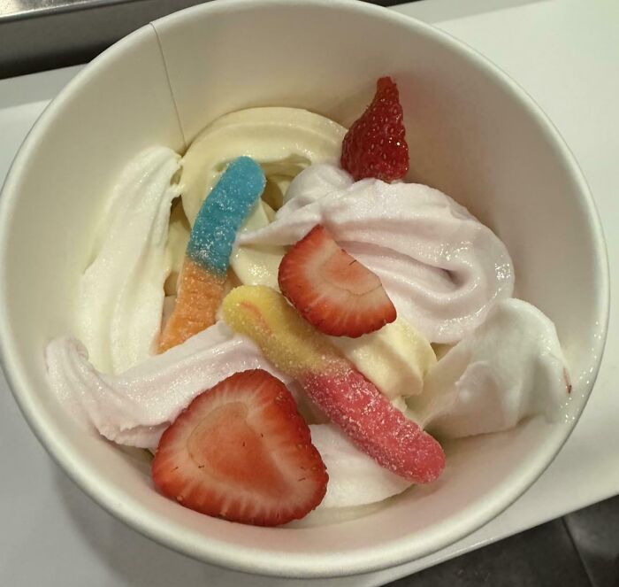 Frozen yogurt topped with gummy worms and fresh strawberries, a popular girl dinner combo idea.
