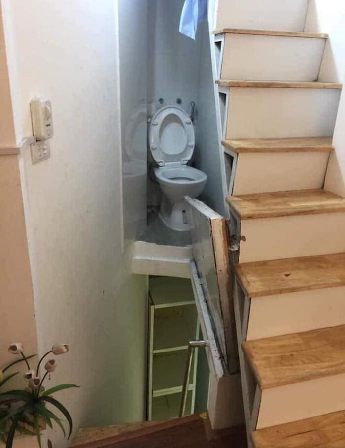 Unusual small bathroom with a toilet tucked under stairs in a unique Zillow home design.