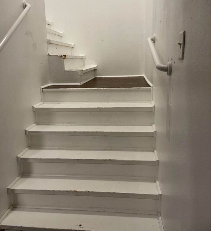 Worn white staircase with a damaged upper step and wood flooring, part of unusual Zillow homes to see and believe.