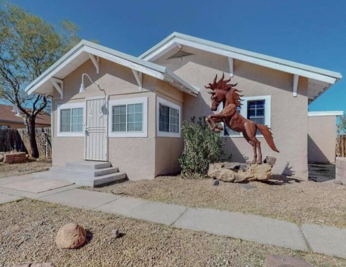 Unique Zillow home exterior with a large horse sculpture and desert landscaping under a clear blue sky.
