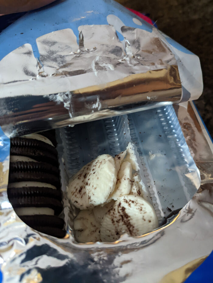 Partially eaten Oreo cookie filling separated from cookies inside opened snack package showing frustrating snack experience.