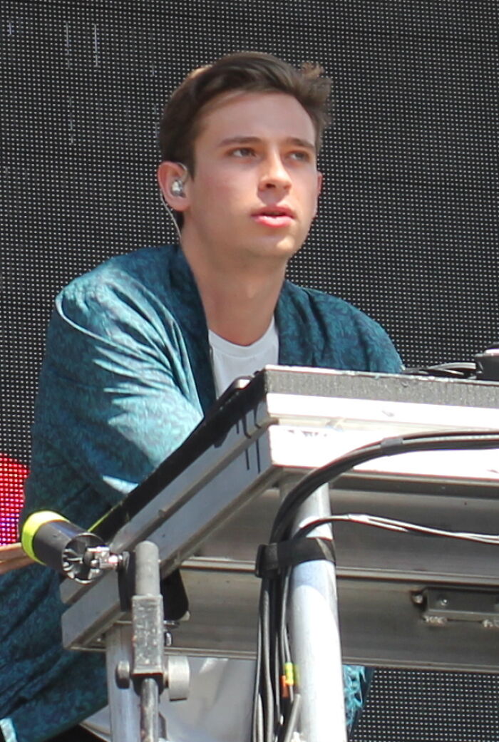 Flume performing live on stage focused on music equipment with earpiece in casual blue jacket