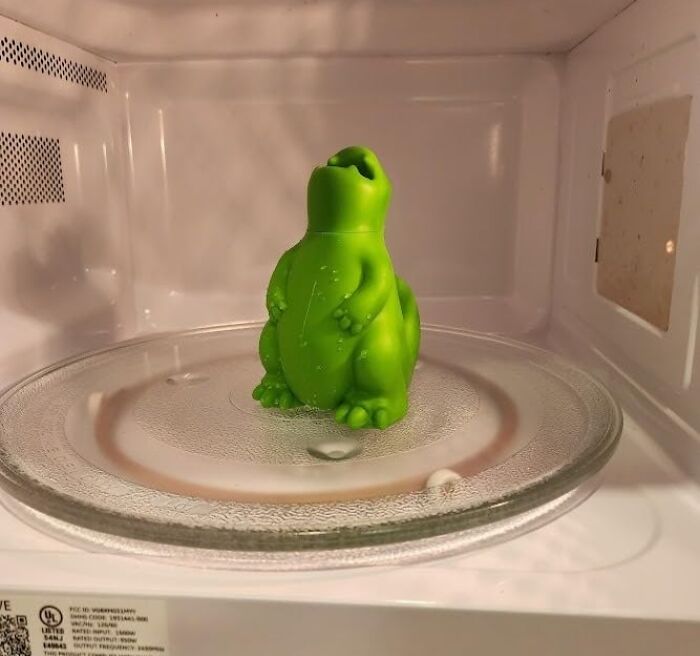 Green dinosaur-shaped kitchen gadget inside a microwave, showcasing new kitchen finds trending now.