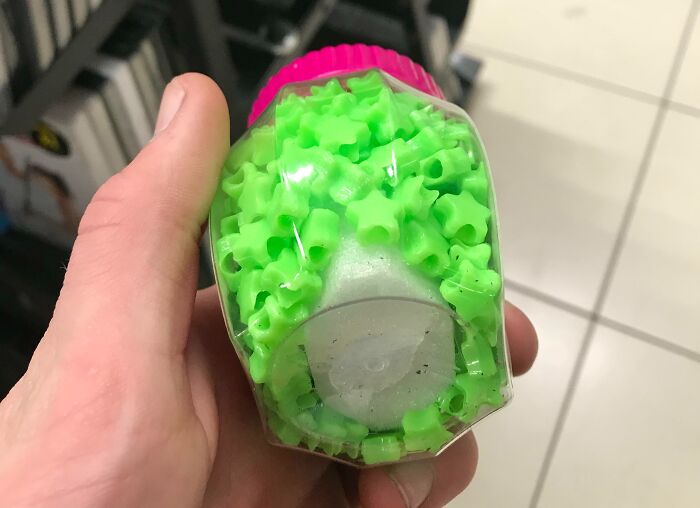 Hand holding misleading packaging filled with small green star-shaped objects, illustrating product packaging deception.