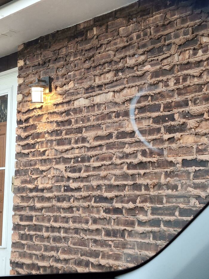 Uneven brick wall repair with messy mortar near a porch light showing people not even trying job examples.