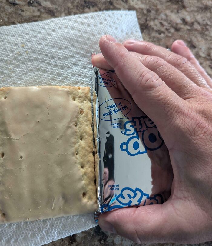 Hand opening toaster pastry packaging showing much smaller product than expected, highlighting misleading packaging by companies.