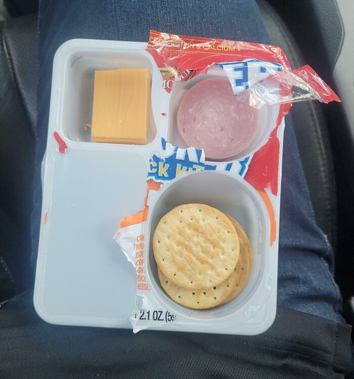 Misleading packaging shows small portions of cheese, lunch meat, and crackers in a snack kit that appears larger than actual contents.