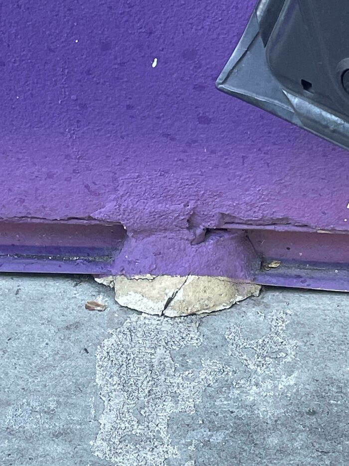 C*****d concrete piece used as a makeshift support under a purple painted metal structure showing people not even trying.