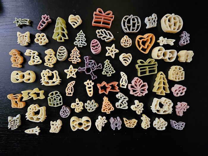 Various shaped and colored pasta pieces neatly arranged in rows on a black surface, showcasing all things knolled order.