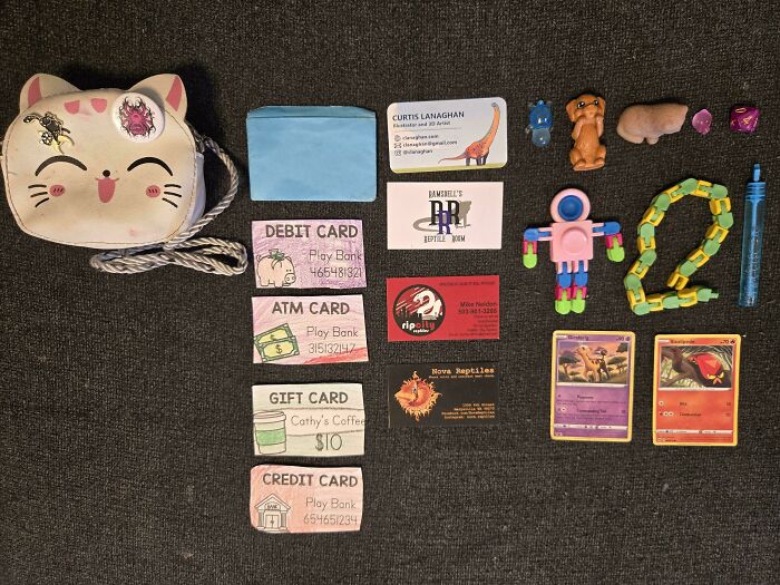 Neatly arranged small items including cards, toys, and a cat purse showcasing satisfying order knolled style.