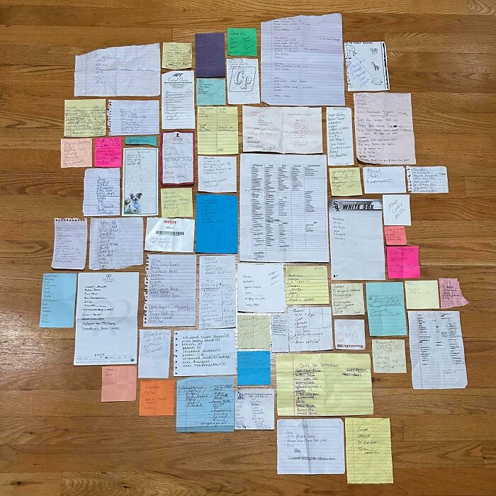 Neatly arranged collection of various handwritten notes and lists on colorful papers placed on wooden floor, satisfying order.