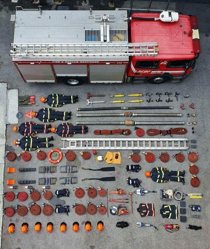 Fire truck and neatly arranged firefighting gear and equipment displayed in perfect order on pavement.