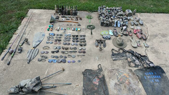 Neatly knolled collection of fishing gear, sunglasses, tools, and outdoor items arranged on concrete surface.