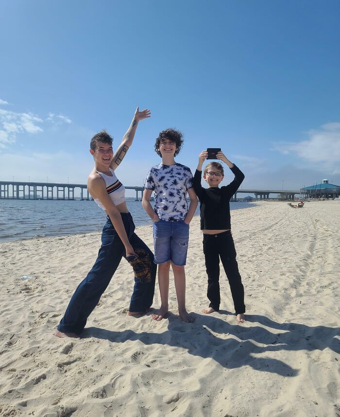 Three happy children on a sunny beach showing kindness and joyful moments restoring faith in humanity.