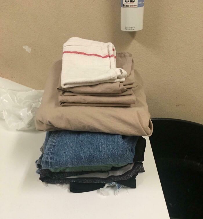 Folded clothes including jeans and towels neatly stacked on a white surface showing faith in humanity restored acts.