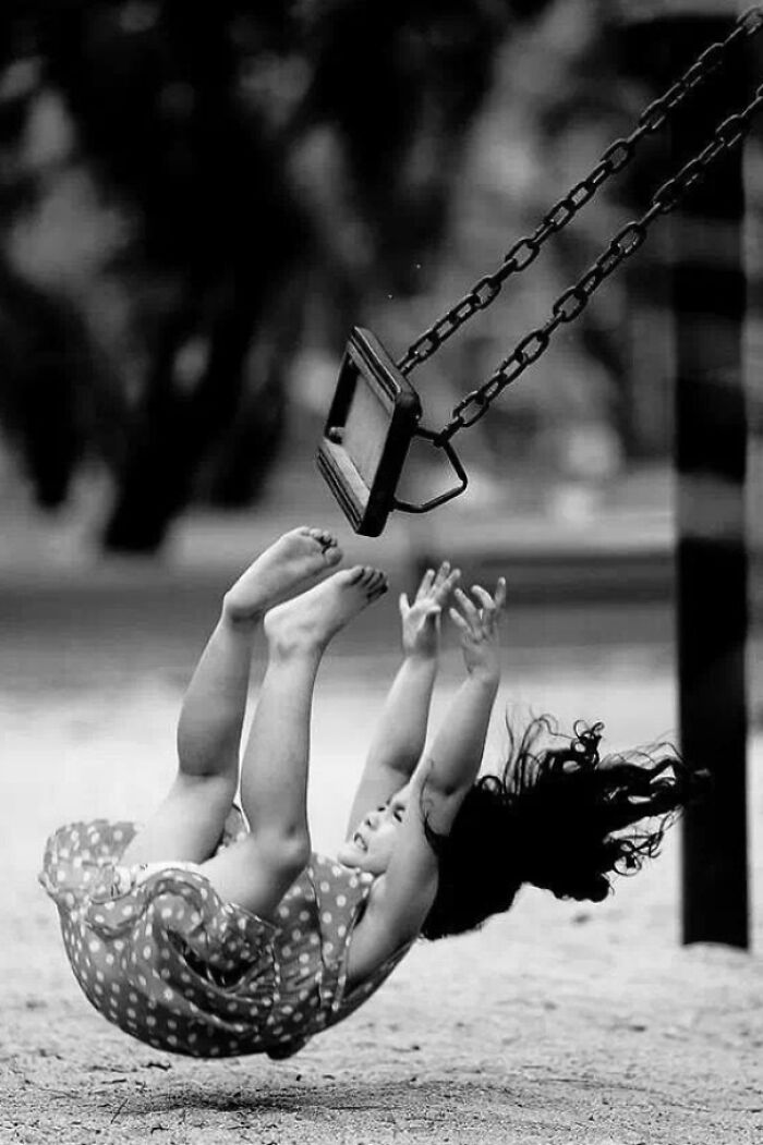 Child falling off a swing captured in a frozen frame, showing motion and emotion without revealing the aftermath.