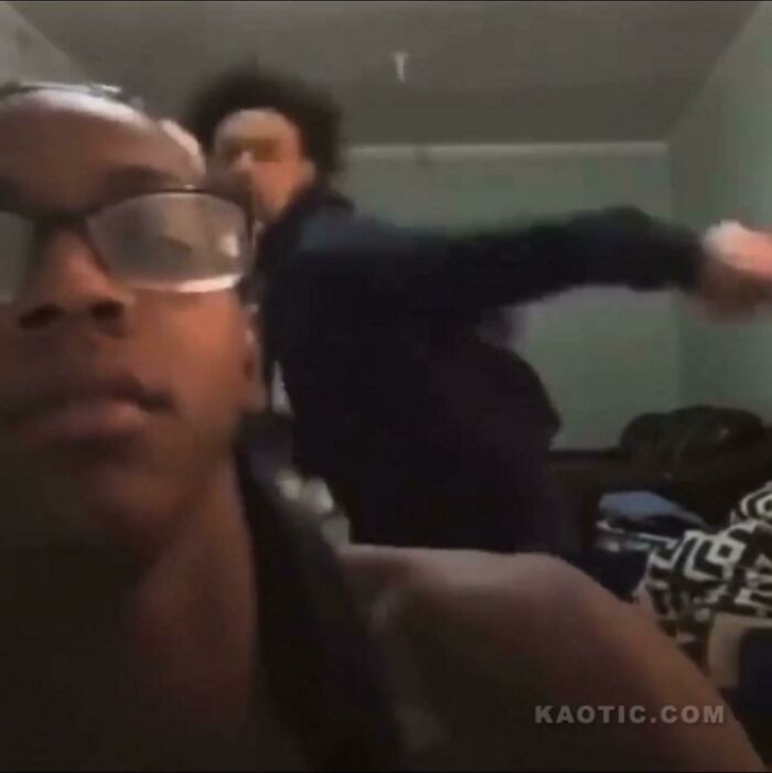 Two young men in a room captured in a frozen frame moment, illustrating impact without showing the aftermath.