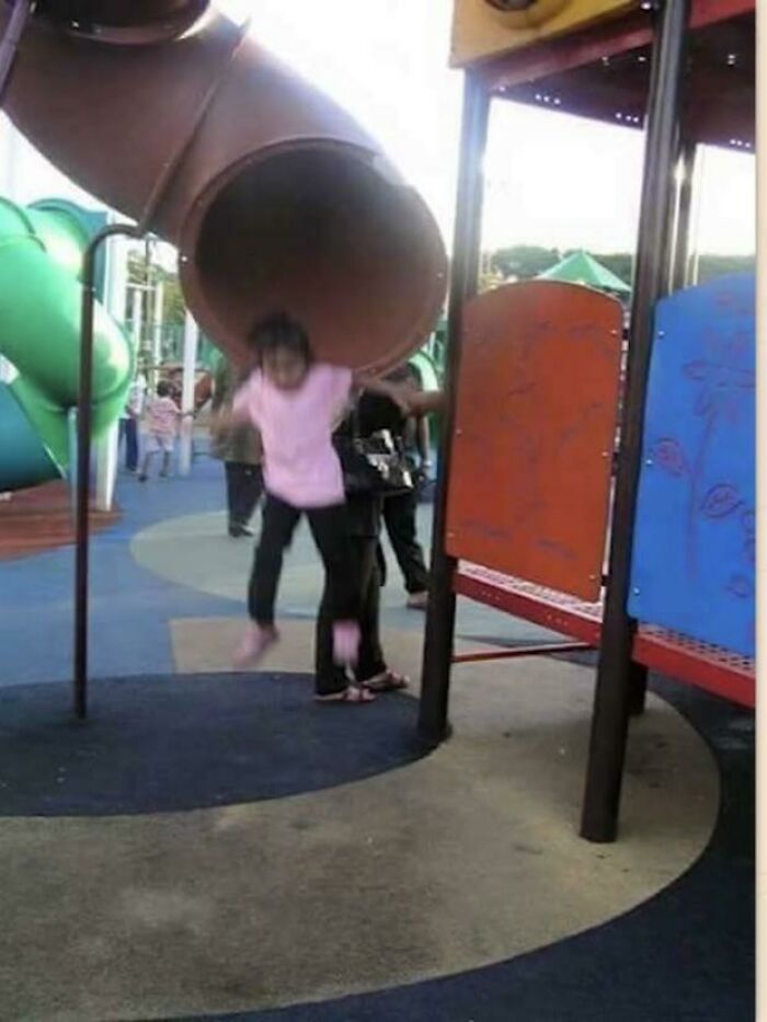 Child captured mid-air at playground slide exit in a frozen frame revealing motion without showing aftermath