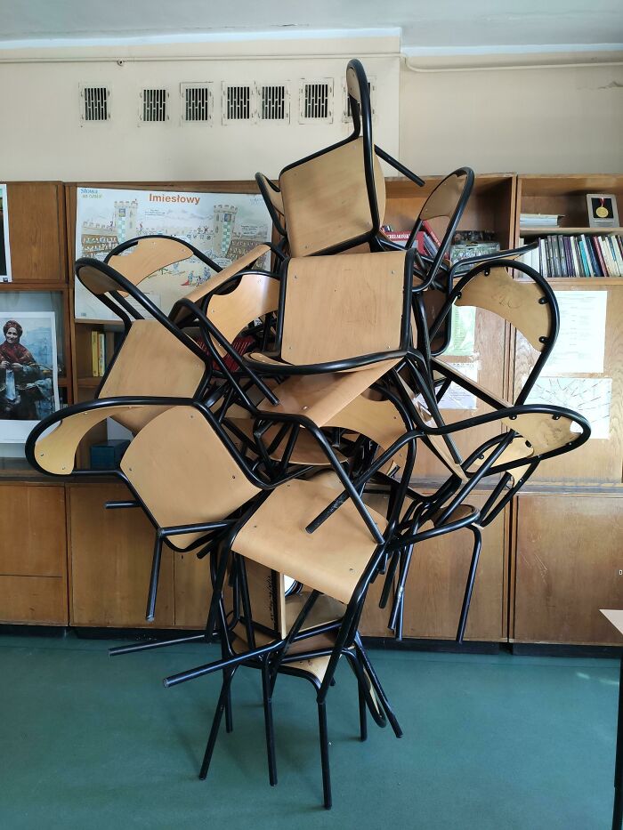 Stack of wooden chairs in a classroom forming a frozen frame capturing a moment without showing the aftermath.