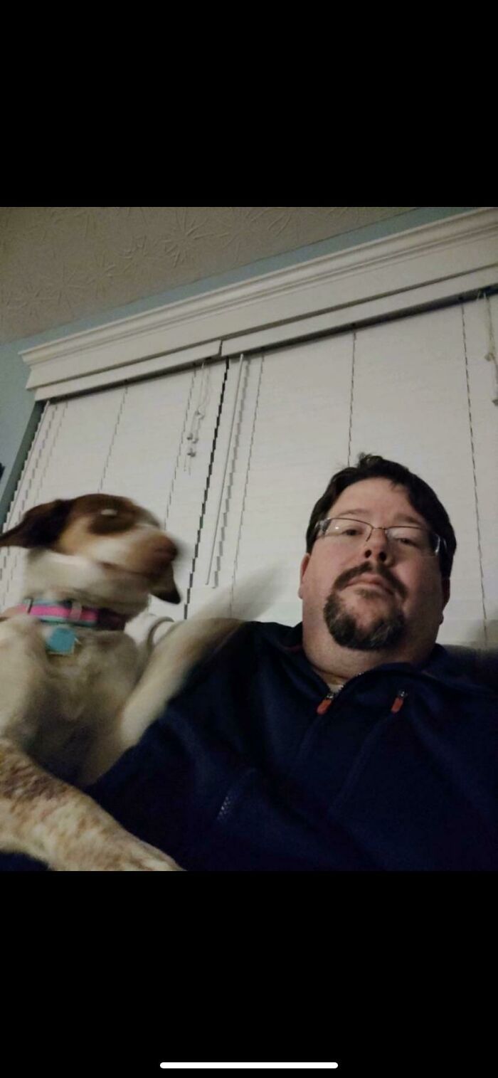 Man wearing glasses with blurred dog paw in motion, a frozen frame capturing action without showing the aftermath.