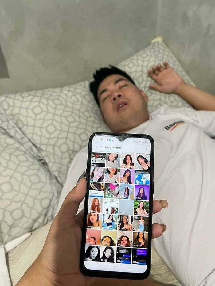 Man lying on bed asleep with phone showing recently deleted photos, capturing frozen frames that tell a story without aftermath.