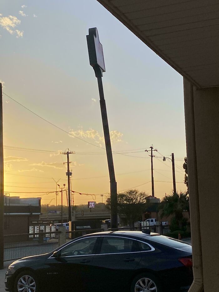 Black car parked under a bent pole at sunset showing frozen frames capturing moments without aftermath.