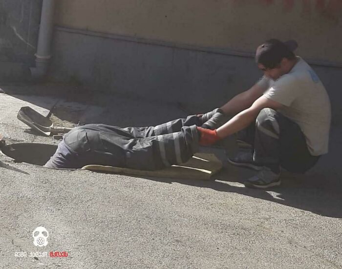 Two men working on a street project captured in a frozen frame showing teamwork without revealing the aftermath.
