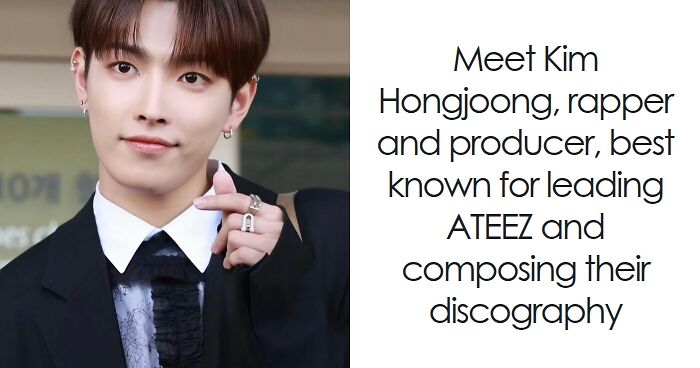 Hongjoong smiling and wearing a black suit and white shirt, known as rapper and producer leading ATEEZ.