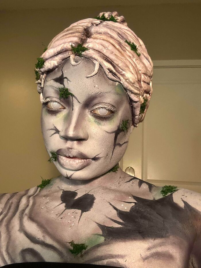 Creative person with body art resembling c*****d statue and moss, showcasing unique creative projects that inspire reflection.