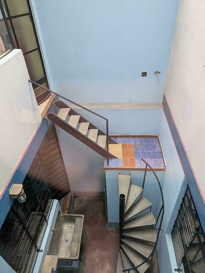 Steep narrow metal spiral and straight stairs inside a small enclosed outdoor Airbnb space needing careful navigation.