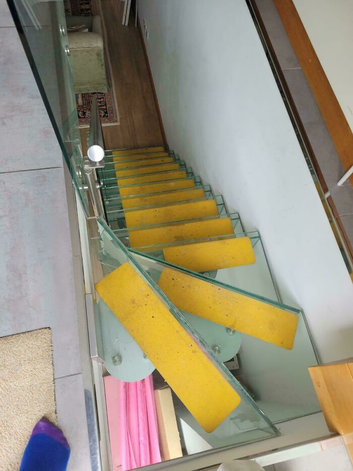 Glass stairs with bright yellow steps in a modern home interior, highlighting the risk of Airbnb stairs needing insurance.