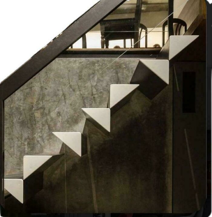Modern staircase with sharp triangular steps against a concrete wall, highlighting Airbnb insurance risks for stairs.