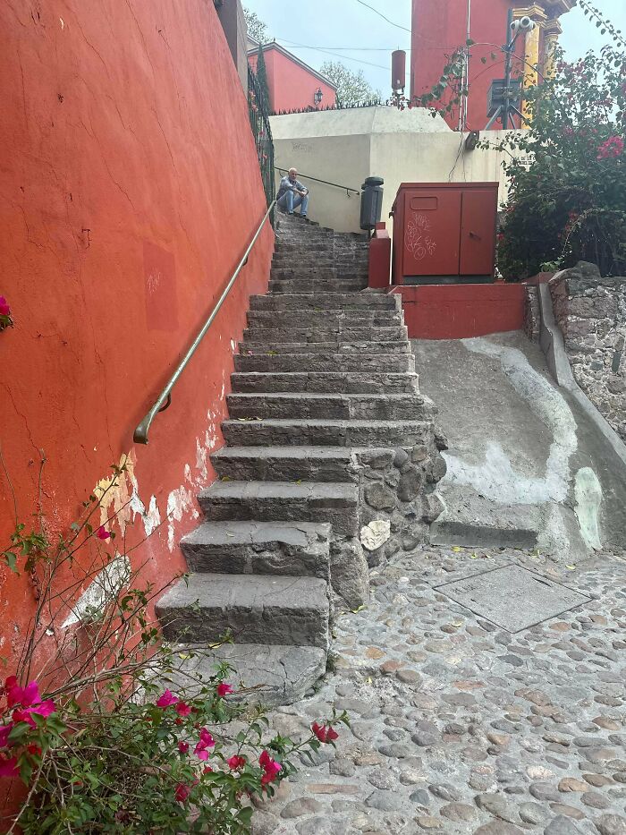 Stone stairs with uneven steps beside a red wall, a person sitting at the top, illustrating Airbnb insurance risks.