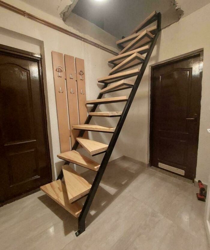Steep wooden stairs with open gaps and no railing inside a room, illustrating Airbnb insanity hazards.