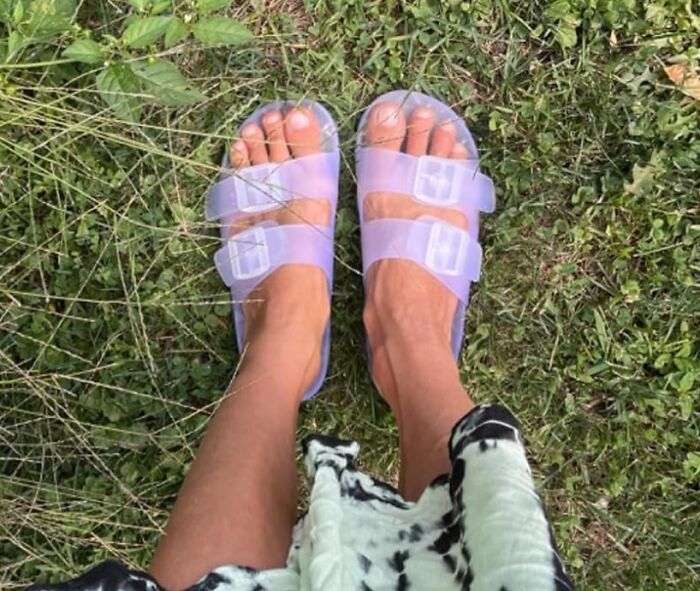 Feet wearing translucent purple novelty sandals standing on grass, showcasing completely unnecessary novelty finds.