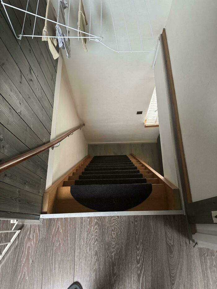 Steep wooden stairs with black carpet treads in a narrow space, illustrating Airbnb insurance risks on challenging stairs.