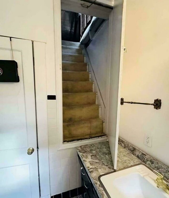 Narrow and steep indoor stairs behind a bathroom door, highlighting Airbnb insurance risks and safety concerns.