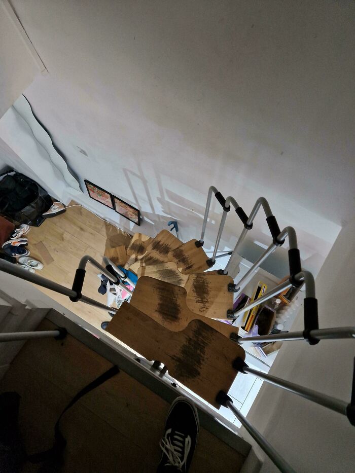 Narrow wooden spiral stairs with metal rails in an Airbnb rental, highlighting the need for insurance due to risks.