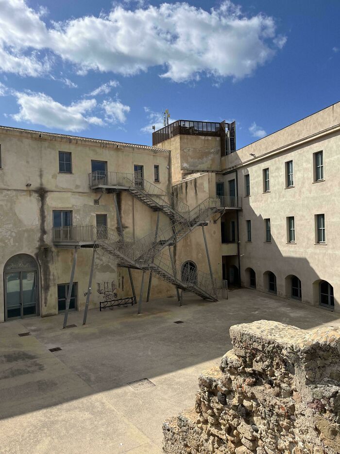 Old building courtyard with a complex metal staircase structure highlighting Airbnb stairs and insurance safety concerns.
