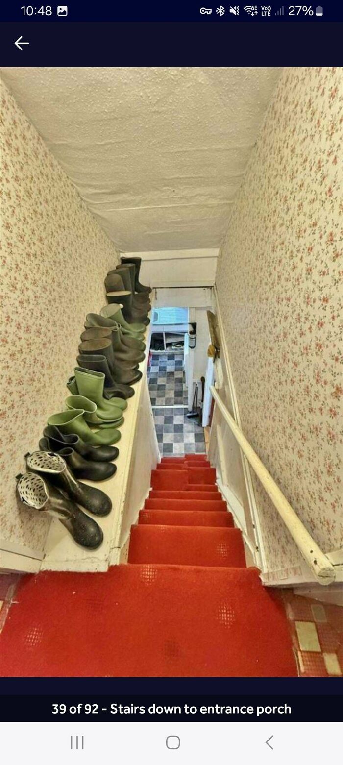Steep narrow staircase with red carpet and a row of rain boots on the wall, illustrating Airbnb stairs needing insurance.