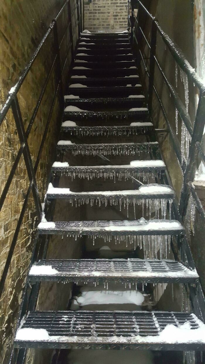 Icy metal stairs covered with snow and icicles between brick walls, illustrating Airbnb insanity risks.