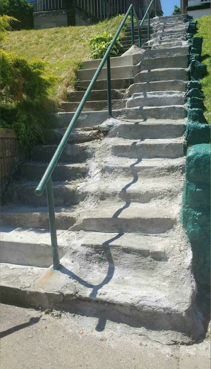 Uneven and worn outdoor concrete stairs with a metal handrail, illustrating the need for Airbnb insurance safety precautions.